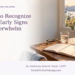 Open notebook, eyeglasses and a glass of water on a sunlit table beside a window.